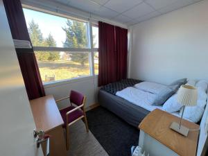 a bedroom with a bed and a desk and a window at Godaland Guesthouse and Glamping in Hlíðarendi