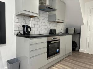 a kitchen with white cabinets and a black counter top at Studio Flat in Luton Town Centre in Luton