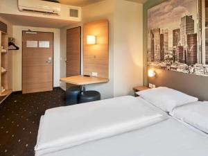 a hotel room with two beds and a desk at B&B Hotel Frankfurt-West in Frankfurt