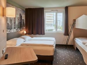 a hotel room with two beds and a window at B&B Hotel Frankfurt-West in Frankfurt/Main