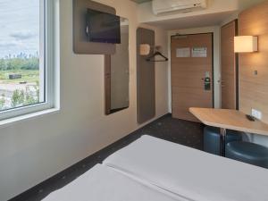 Zimmer mit einem Schreibtisch, einem TV und einem Fenster in der Unterkunft B&B Hotel Frankfurt-West in Frankfurt am Main
