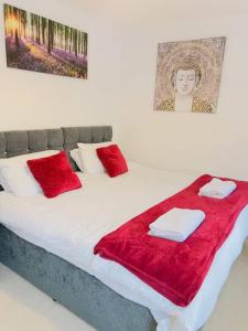 a bed with red blankets and pillows on it at Starview Apartment-Vitoria in Lexden