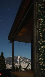 a christmas tree in front of a house with a mountain at Chilloutzonе - Будинок з безкоштовним джакузі та кінотеатром in Slavske