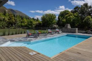 a swimming pool with four chairs and a table at Luxury Eco Apt w Pool Gym & Sauna - Adults only in Wanaka
