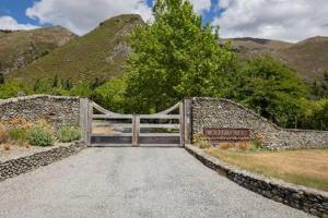 a gate in a stone wall with a sign at Luxury Eco Apt w Pool Gym & Sauna - Adults only in Wanaka