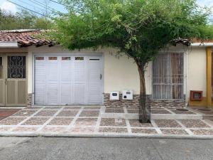 una casa con dos puertas de garaje y un árbol en Casa en Cartago Valle, en Cartago