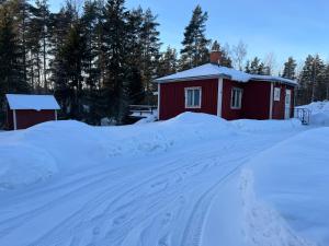 a snow covered road leading to a red building at Lillhuset in Järbo