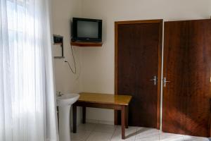 een badkamer met een wastafel en een tv aan de muur bij HOTEL TAIÓ in Taió