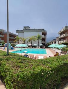 a swimming pool with chairs and umbrellas and a building at Le Case di Zu Zù in Mascali