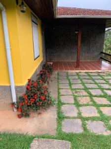 a yellow house with a flower bush with red flowers at Sitio dos Sabias in Ibiúna