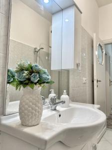 a bathroom with a sink with a vase with flowers in it at Maison Grimaldi Roma in Rome