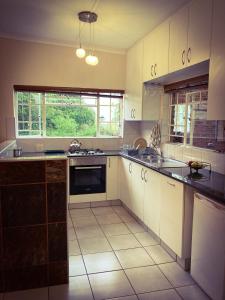 a large kitchen with white cabinets and a sink at The Blow-Inn Farmer, Sunrise Cottage in Howick