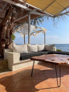 un patio con sofá, mesa y el océano en Hotel Avlakia, en Kokkari