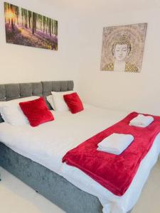 a bed with red blankets and pillows on it at 2 Bedroom Flat in Colchester in Colchester