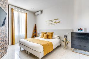 a white bedroom with a bed and a television at Le Angioine Rooms in Naples