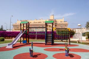 um parque infantil em frente a um edifício com escorrega em Apartamento planta baja Residencial Aquamarina by costablancarent em Denia