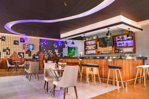 a restaurant with a bar and tables and chairs at Romeos Hotel Luzira Kampala in Kampala