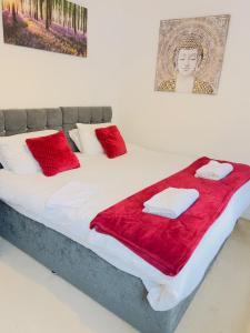 Una cama con almohadas rojas y toallas. en 2 Bedroom Flat in Colchester, en Colchester
