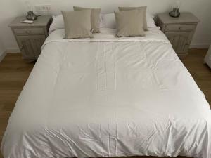 ein großes weißes Bett in einem Schlafzimmer mit zwei Nachttischen in der Unterkunft Málaga-Centro in Málaga