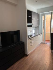 a kitchen with white cabinets and a flat screen tv at Appartamento sul lungomare in centro Ladispoli in Ladispoli