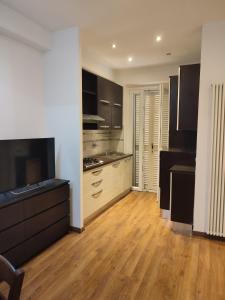 a kitchen with black cabinets and a wooden floor at Appartamento sul lungomare in centro Ladispoli in Ladispoli
