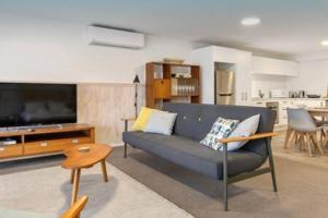 a living room with a blue couch and a television at Wanaka 'Mount Iron Studio' with private terrace in Wanaka