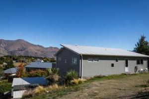 a small house in a field with mountains in the background at Wanaka 'Mount Iron Studio' with private terrace in Wanaka