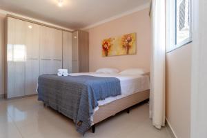 um quarto com uma cama com um cobertor azul em Apto com 3 quartos climatizados nos Ingleses HK2120 em Florianópolis