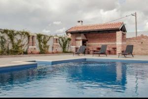 a swimming pool with two chairs next to a building at Apartman Rocky in Petrovija