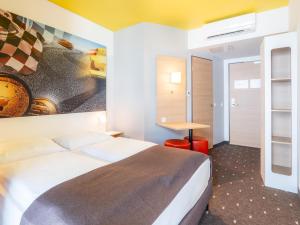 B&B Hotel Stuttgart-Zuffenhausen في شتوتغارت: غرفة فندق فيها سرير و لوحة على الحائط