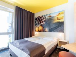 a bedroom with a bed with a painting on the wall at B&B Hotel Stuttgart-Zuffenhausen in Stuttgart