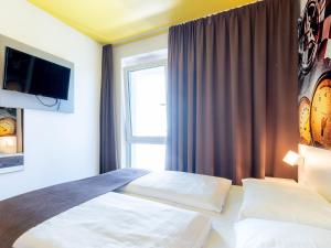 B&B Hotel Stuttgart-Zuffenhausen في شتوتغارت: غرفه فندقيه بسرير ونافذه