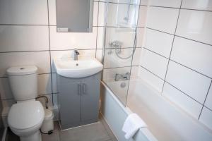 a bathroom with a toilet and a sink and a tub at Ashburnham Hotel in Pembrey +31 photos