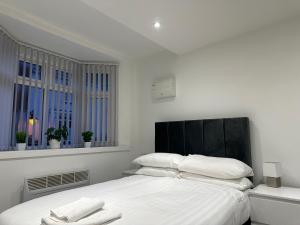 a white bedroom with a large bed with white pillows at Modern Apartment in Luton town Centre in Luton
