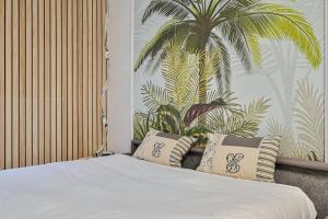 1 dormitorio con 1 cama con almohadas y un mural de palmeras en Le Sunny - Proche Paris - Terrasse, en Livry-Gargan