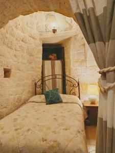 a bedroom with a bed in a stone wall at La Rosa dei Trulli B&B in Alberobello