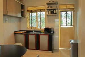 Elle comprend une petite cuisine avec un évier et une fenêtre. dans l'établissement S A Apartments, à Kampala