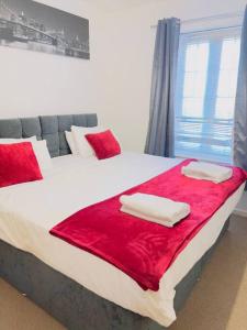 a bedroom with a large bed with red sheets and pillows at Starview Apartment 101 in Colchester