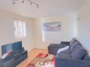 a living room with a blue couch and a flat screen tv at Starview Apartment 101 in Colchester