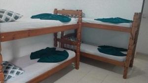 two bunk beds in a room with green clothes on them at Pousada restaurante recanto do Marimar in Paraty