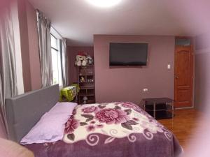 - une chambre avec un lit doté d'une couverture fleurie et d'une télévision dans l'établissement Habitación doble con balcón. bonita vista, à Cajamarca