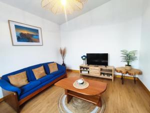 a living room with a blue couch and a tv at GATEONE AL Airport View House in Machico