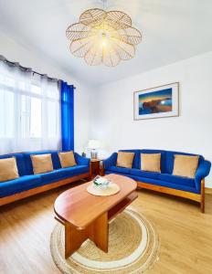 een woonkamer met blauwe banken en een tafel bij GATEONE AL Airport View House in Machico