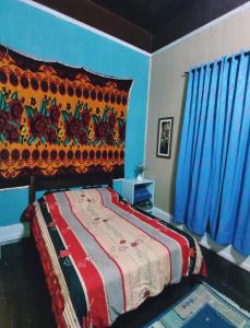 1 dormitorio con 1 cama con paredes azules y cortinas azules en Pousada Shamballah Paranapiacaba en Paranapiacaba