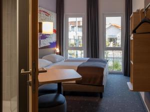 a hotel room with a bed and a desk and windows at B&B HOTEL Bad Hersfeld in Bad Hersfeld