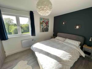 a bedroom with a large bed and a chandelier at Gorgeous modern furnished cabin in Steyning in Steyning
