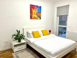 uma cama branca com duas almofadas amarelas num quarto em Comfortable apartment in a complex Great Britain em Lviv