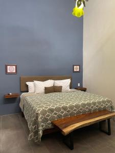 Quinta La Perla في غواذالاخارا: غرفة نوم بها سرير مع مقعد خشبي بجانبها