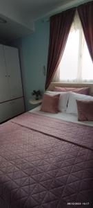 a bedroom with a bed with a pink comforter and a window at MarilidiaHouse in Kardhoulianós
