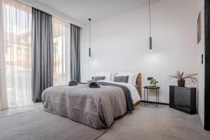 a white bedroom with a bed and a large window at Urban city apartment in Visoko